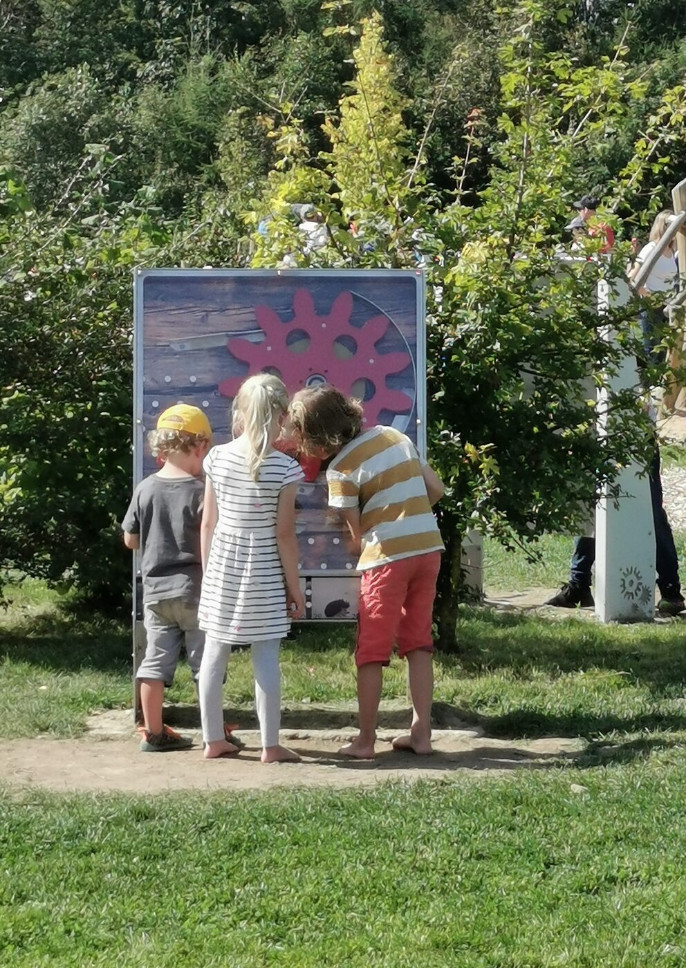 Drei Kinder spielen an der interaktiven Murmel-die-Murmel-Station